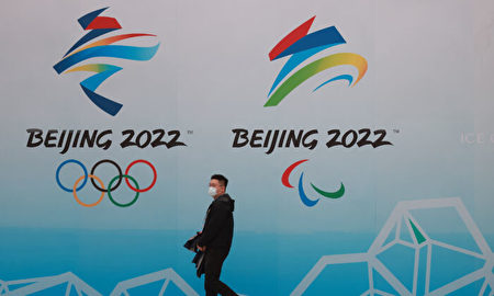 BEIJING, CHINA - APRIL 09: A Chinese man wears a protective mask as he walk in front the logos of the 2022 Beijing Winter Olympics at National Aquatics Centre on April 9, 2021 in Beijing, China. A "Meet in Beijing" ice test event for the 2022 Winter Olympics will be held from April 1-10. (Photo by Lintao Zhang/Getty Images)