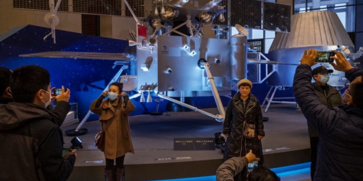 BEIJING, CHINA - MARCH 02: Visitors stand in front of equipment from China's space program that is part of a display at the National Museum of China on March 2, 2021 in Beijing, China. China's mission to the Moon marked the first time in 40 years that fresh lunar rock samples were returned to Earth. The unmanned spacecraft, called Chang-e 5, collected roughly 4 pounds of rock and debris from a region of the Moon's surface that had not been previously explored. China has been pouring billions of dollars into its ambitious space program that aims to land astronauts on the Moon by 2030. Scientists in the U.S. say the new lunar material could help to better understand the Moon's evolution. (Photo by Kevin Frayer/Getty Images)