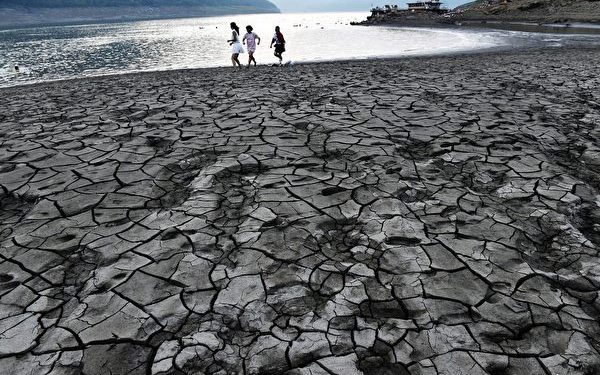 This photo taken on August 24, 2016 shows people walking along the dried and cracked river beach of the Yangtze River in Yunyang county in Chongqing.
Chongqing weather station issued a red alert for high temperature for 12 consecutive days from August 14. / AFP / STR / China OUT (Photo credit should read STR/AFP via Getty Images)