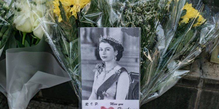 2022年9月9日,在英國駐香港總領事館外,弔唁的民眾在伊麗莎伯二世的照片旁獻上花束。(Getty Images)