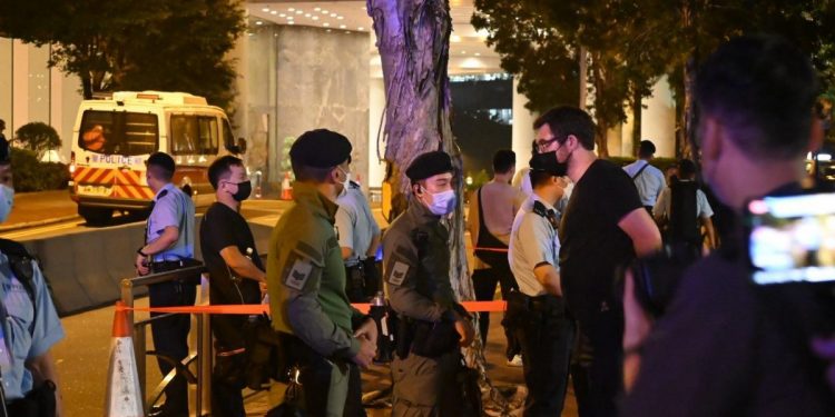港人19日在英領事館外悼念英女王期間，一名身著黑衣的吹口琴男子（左三）被警方截查。（推特圖片）