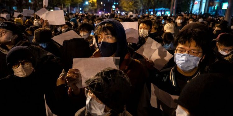 2022年11月27日，在中國北京，抗議者舉着一張反對審查制度的白紙，以抗議中共防疫「清零」政策。 (圖片： Kevin Frayer/Getty Images)