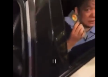 坐在車後排的男子亮出警官證，質問「這能不能走」。（視頻截圖）