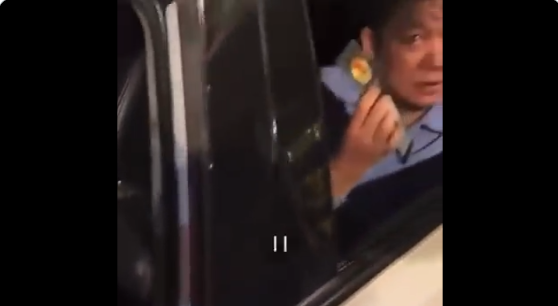 坐在車後排的男子亮出警官證,質問「這能不能走」。(視頻截圖)