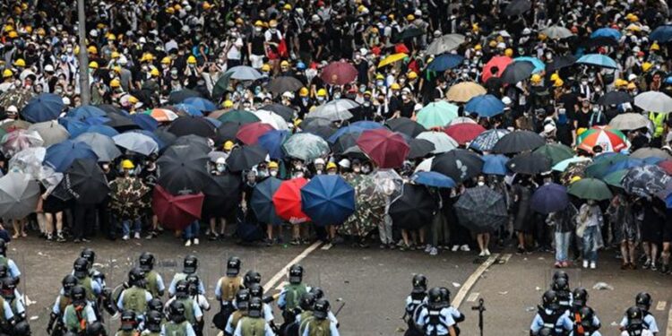2019年6月12日,香港民眾戴著口罩拿著雨傘走上街頭,抗議香港政府不顧反對聲浪,準備通過《逃犯條例》。(Getty Images)
