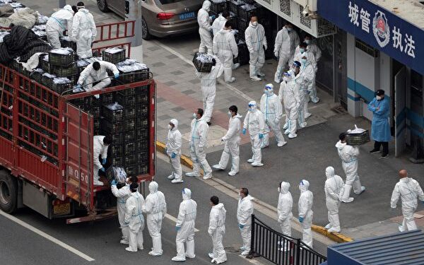 This photo taken on April 5, 2022 shows people wearing personal protective equipment (PPE) as they transfer daily food supplies and necessities for local residents during the Covid-19 lockdown in Shanghai. - China OUT (Photo by AFP) / China OUT (Photo by STR/AFP via Getty Images)