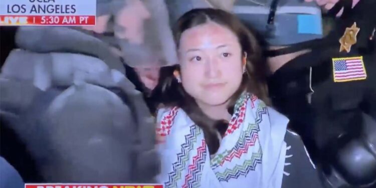 一名參加加州大學洛杉磯分校反猶騷亂者被捕,面紗和口罩拿掉後赫然驚見華人面孔(網絡視頻截圖)