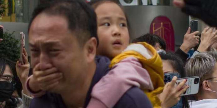 中共輿論控制再上新台階 外聘高層次人才因接受外媒採訪被驅逐。圖為一小女孩摀住爸爸的嘴,不讓他為「鮮花哥」向警察求情。2022年11月,烏魯木齊因封控導致居民無法在火災中逃生,十多人被活活燒死,在上海爆發了大規模的抗議,「鮮花哥」也因此被中共抓捕。(網絡圖片)