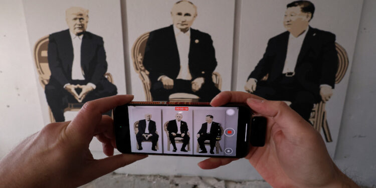 在克里米亞一家藝術畫廊舉行的“雅爾塔 2.0”展覽上,一名遊客對着一幅描繪美國總統川普、俄羅斯總統普京和中共黨魁習近平的藝術作品錄像。(圖片來源:REUTERS/Alexey Pavlishak)