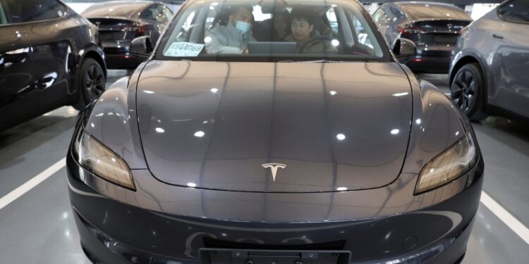 Customers sit in a Tesla Model Y electric vehicle (EV) at the carmaker's delivery centre in Beijing, China January 8, 2025. REUTERS/Florence Lo