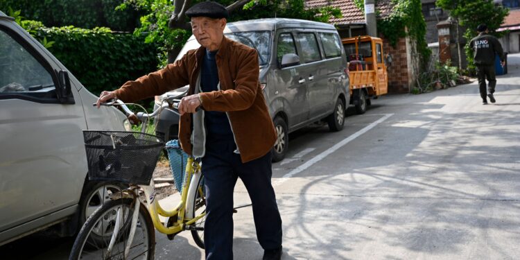 This photo taken on April 27, 2023 shows an elderly man pushing his bicycle through a residential area in Rudong, in eastern China's Jiangsu province. - Rudong once played a pioneering role in the rollout of Beijing's one-child policy. Now, a school lies abandoned and overgrown with vines, while one local university offers courses to retirees. (Photo by Jade Gao / AFP) / To go with AFP story China-India-population-UN, FOCUS by Peter CATTERALL (Photo by JADE GAO/AFP via Getty Images)