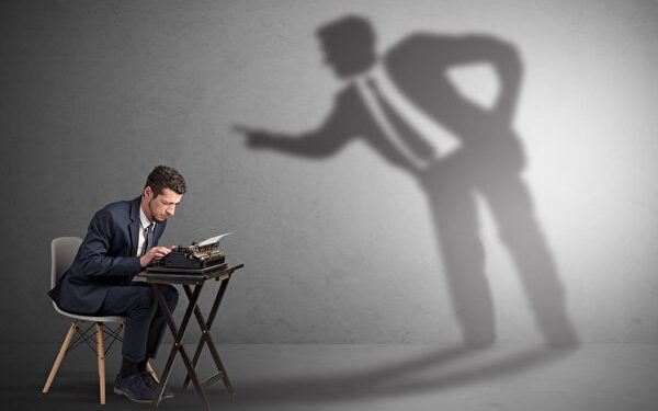 Little man working and a big shadow arguing with him
